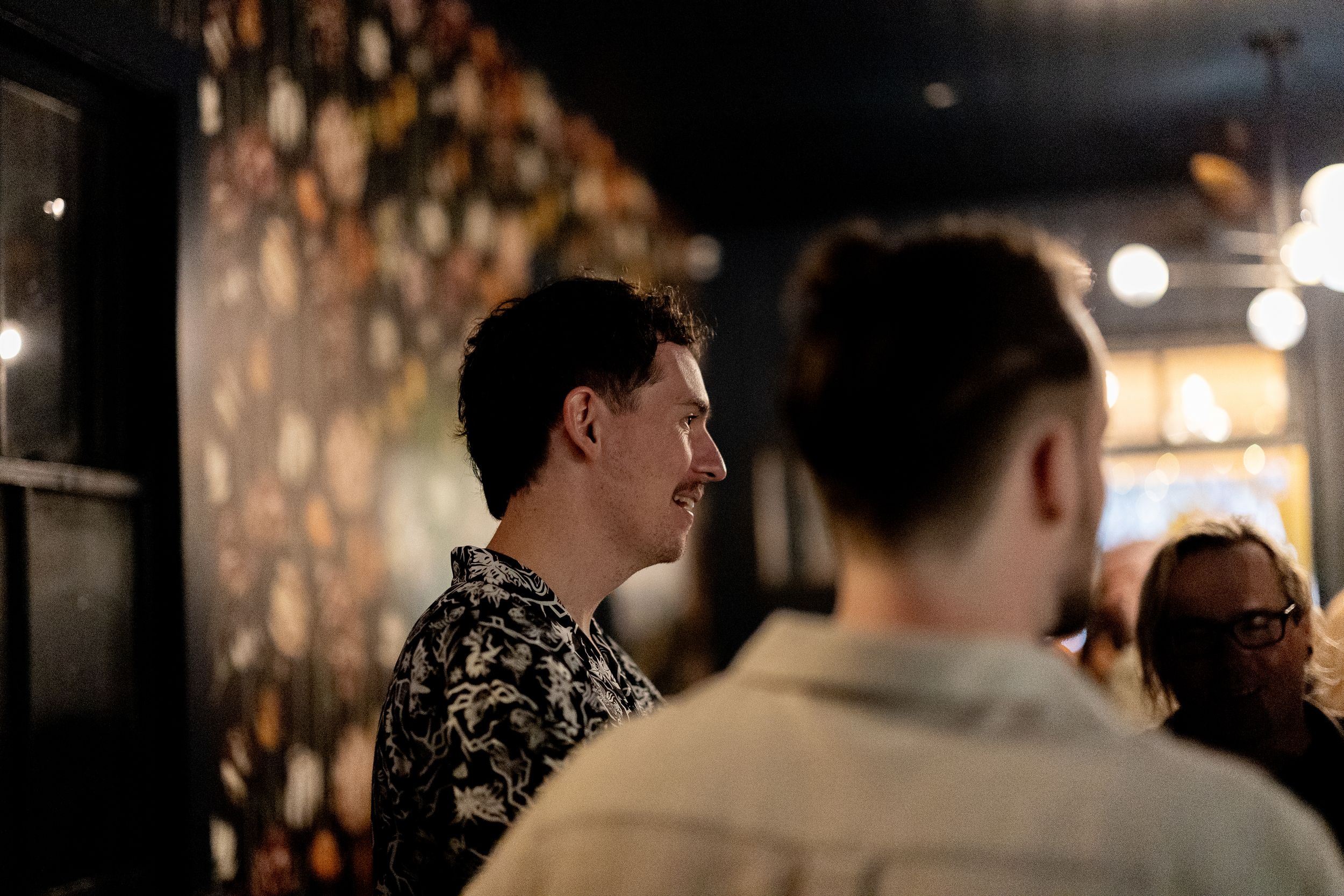 People gathered in a dimly lit bar or restaurant with ambient lighting creating a warm atmosphere.