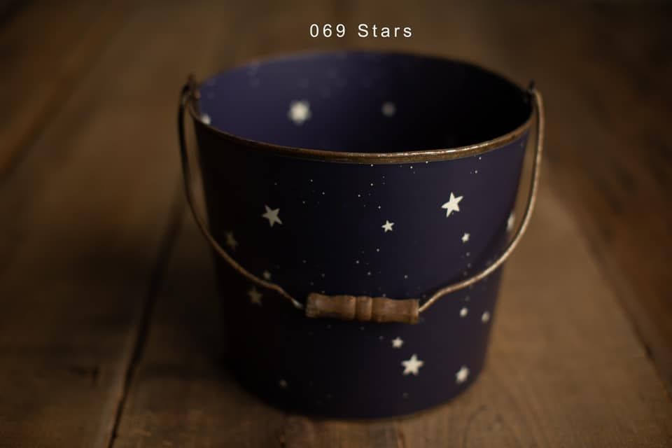 A dark navy blue bucket decorated with gold stars and a wooden handle, labeled 069 Stars on wood surface.