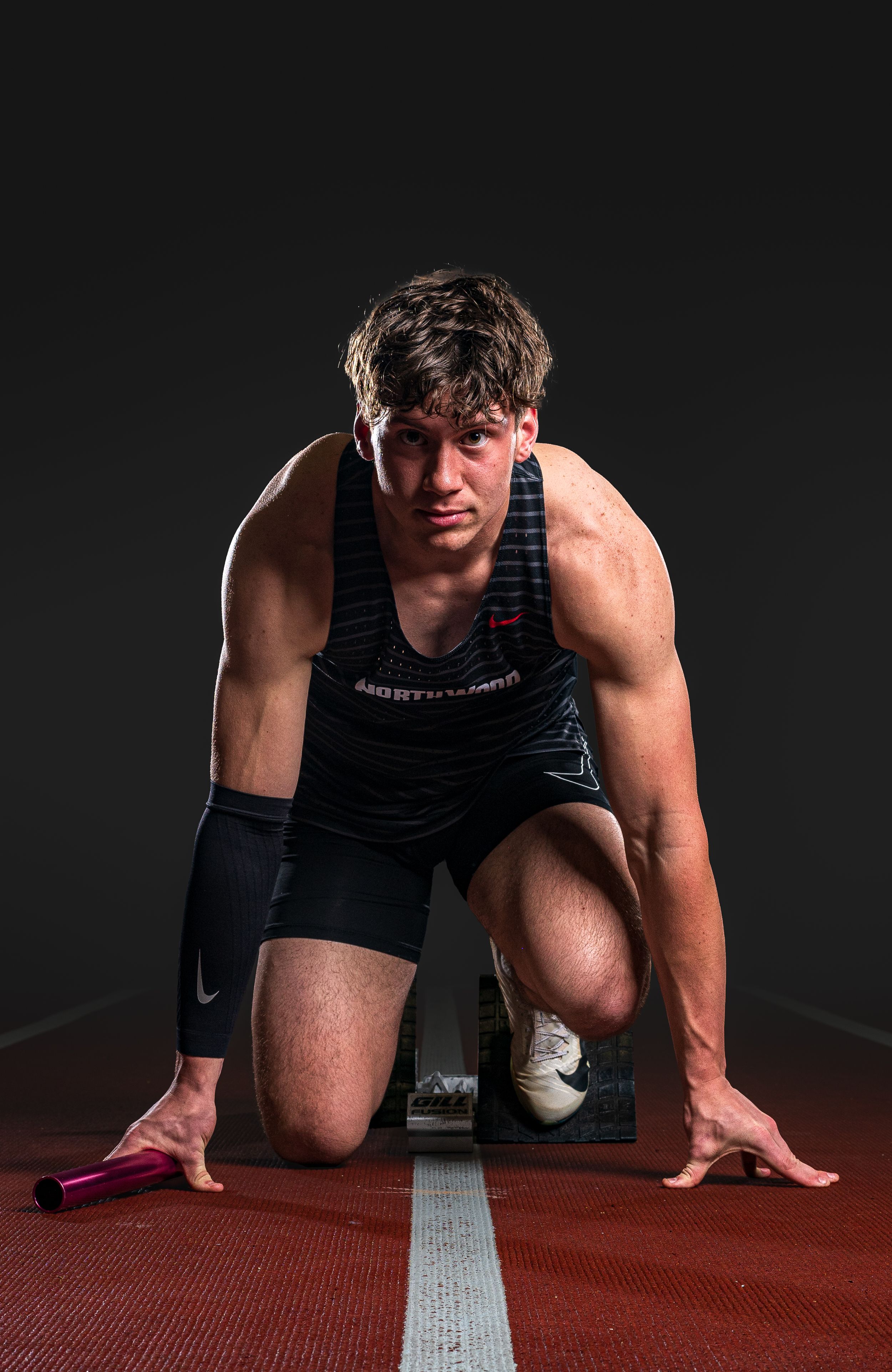 Dynamic Team Media Day Photo of runner in starting position on track wearing dark athletic tank top and shorts - Nappanee, Indiana