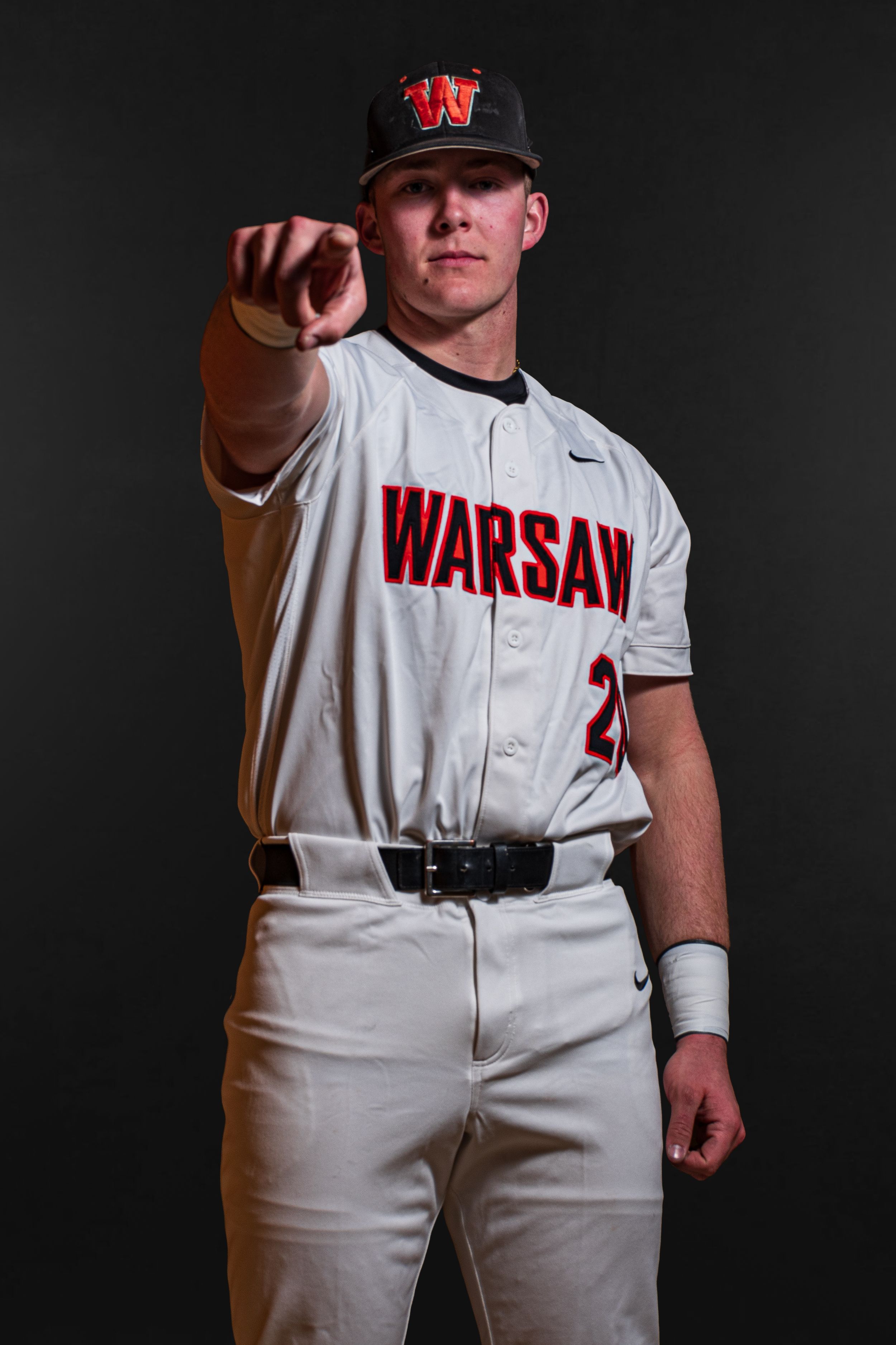 Team Media Day Photo of a baseball player in white Warsaw uniform pointing toward camera - Warsaw, Indiana