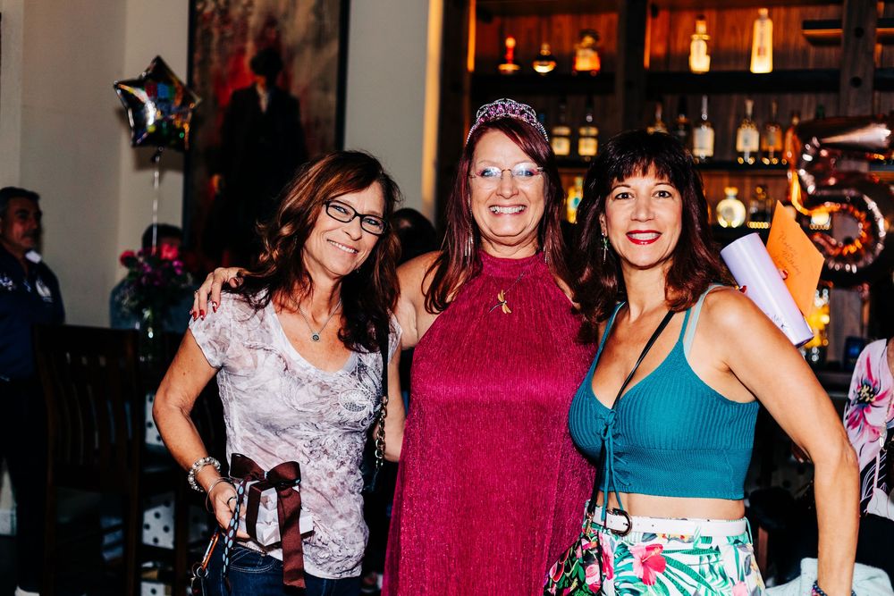 Three friends posing together at a bar celebration with festive decorations at an event in lake worth.