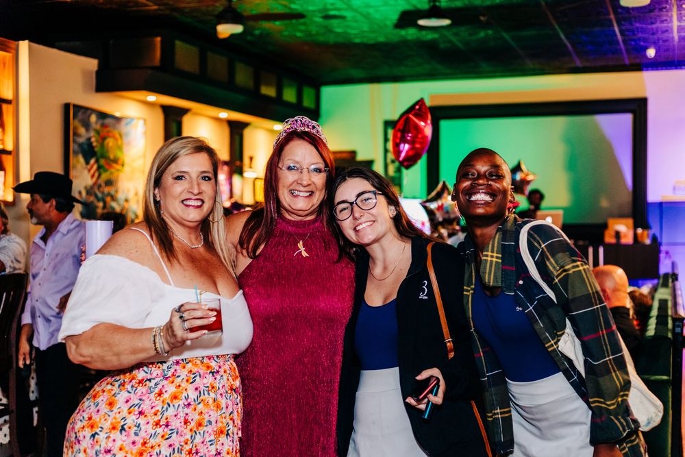 Group of friends posing together at indoor party with colorful lighting at an event in lake worth.