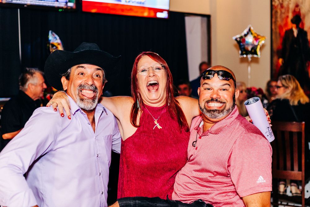 Three friends laughing joyfully together at a party with star decorations at an event in lake worth.
