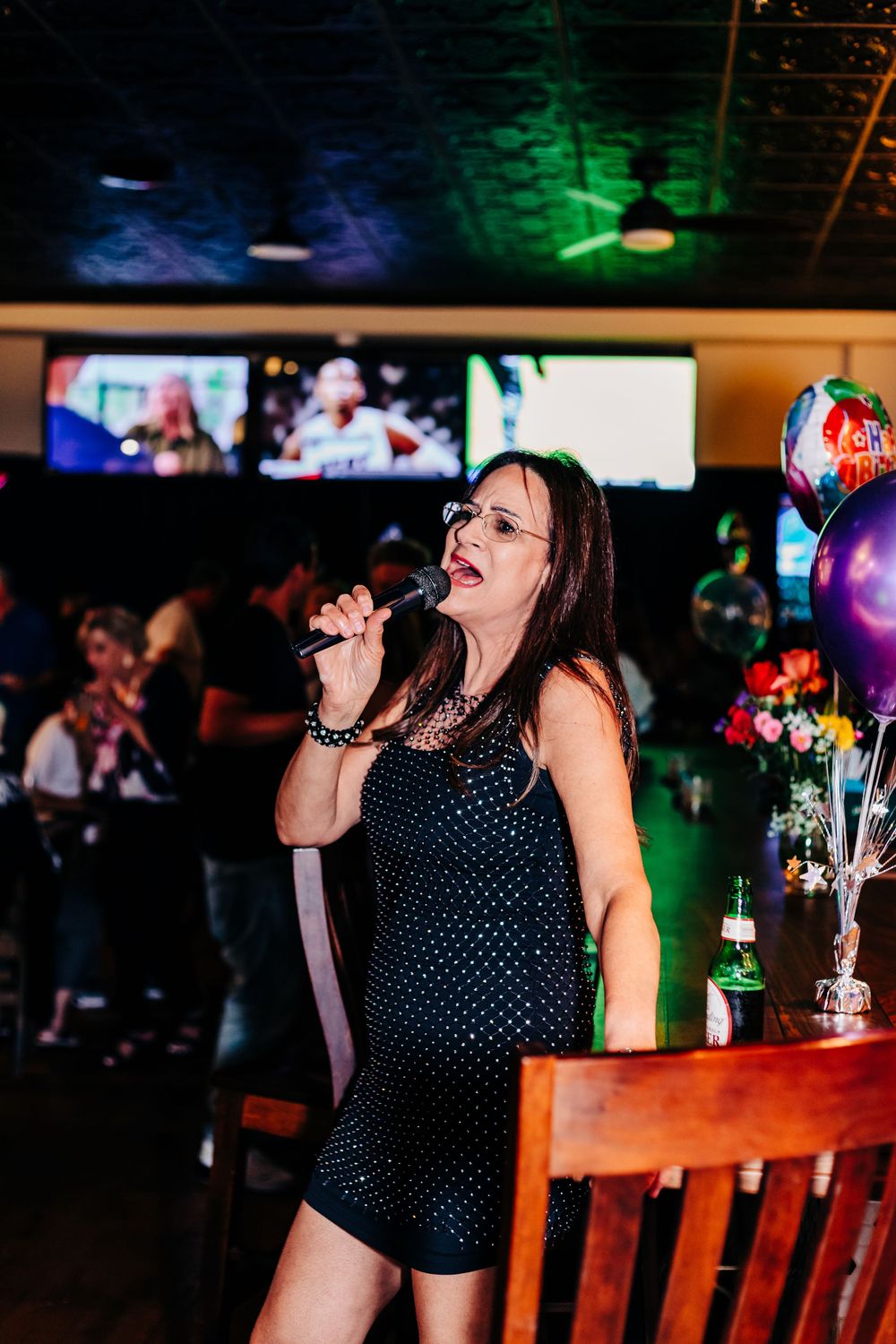Person in polka dot dress singing with enthusiasm at a karaoke bar at an event in lake worth.