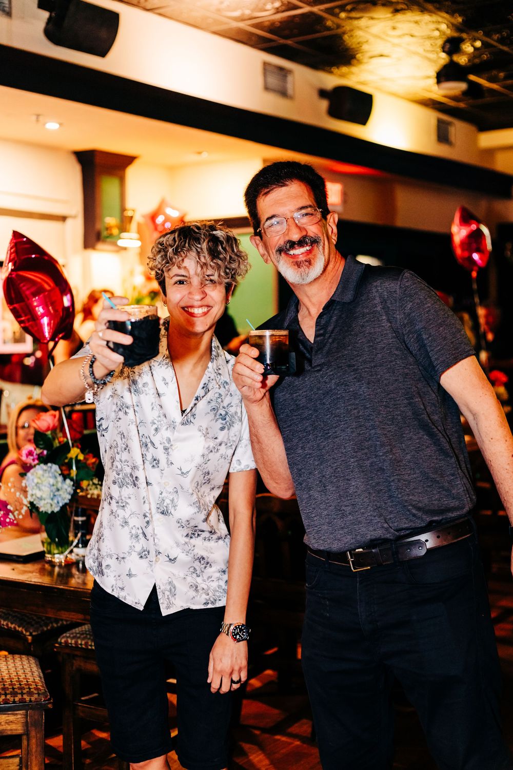 Two people sharing drinks and smiles at a bar with festive decorations at an event in lake worth.