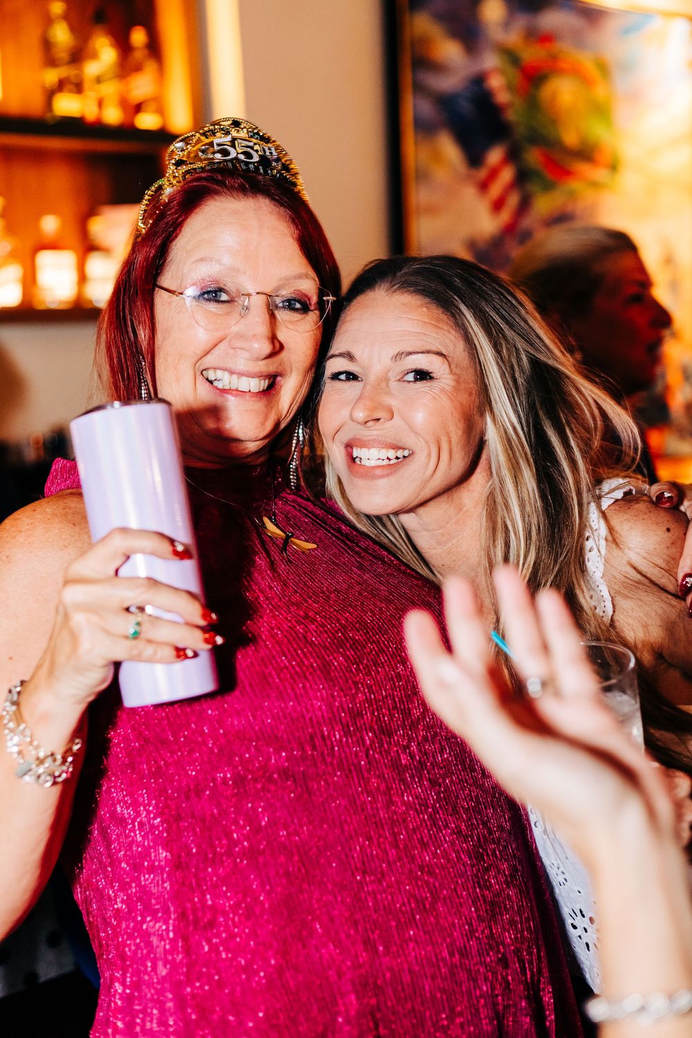 Two partygoers celebrate with drinks and smiles at a festive bar event at an event in lake worth.