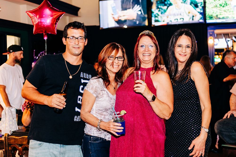 Friends enjoying drinks and socializing at a party with a red star balloon in the background at an event in lake worth.