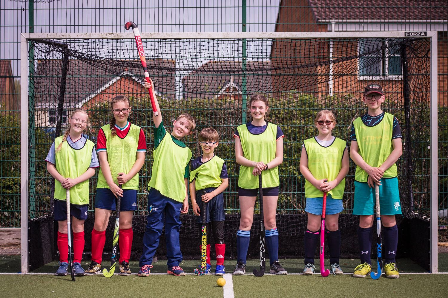 Group of young and happy hockey players at Redditch Hockey Club holding hockey sticks for a team photo