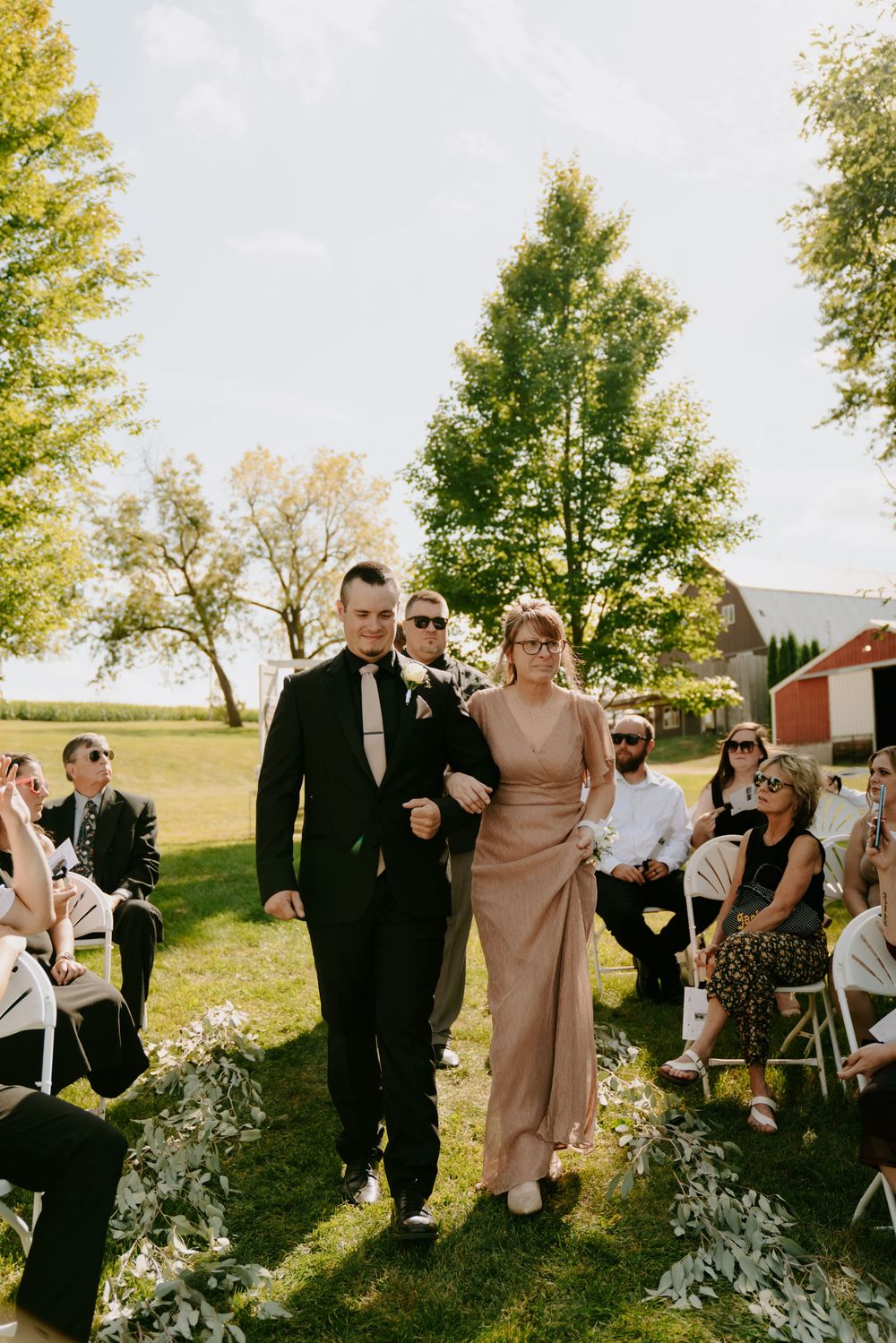 Wedding guests and party members walking through sunny outdoor venue.