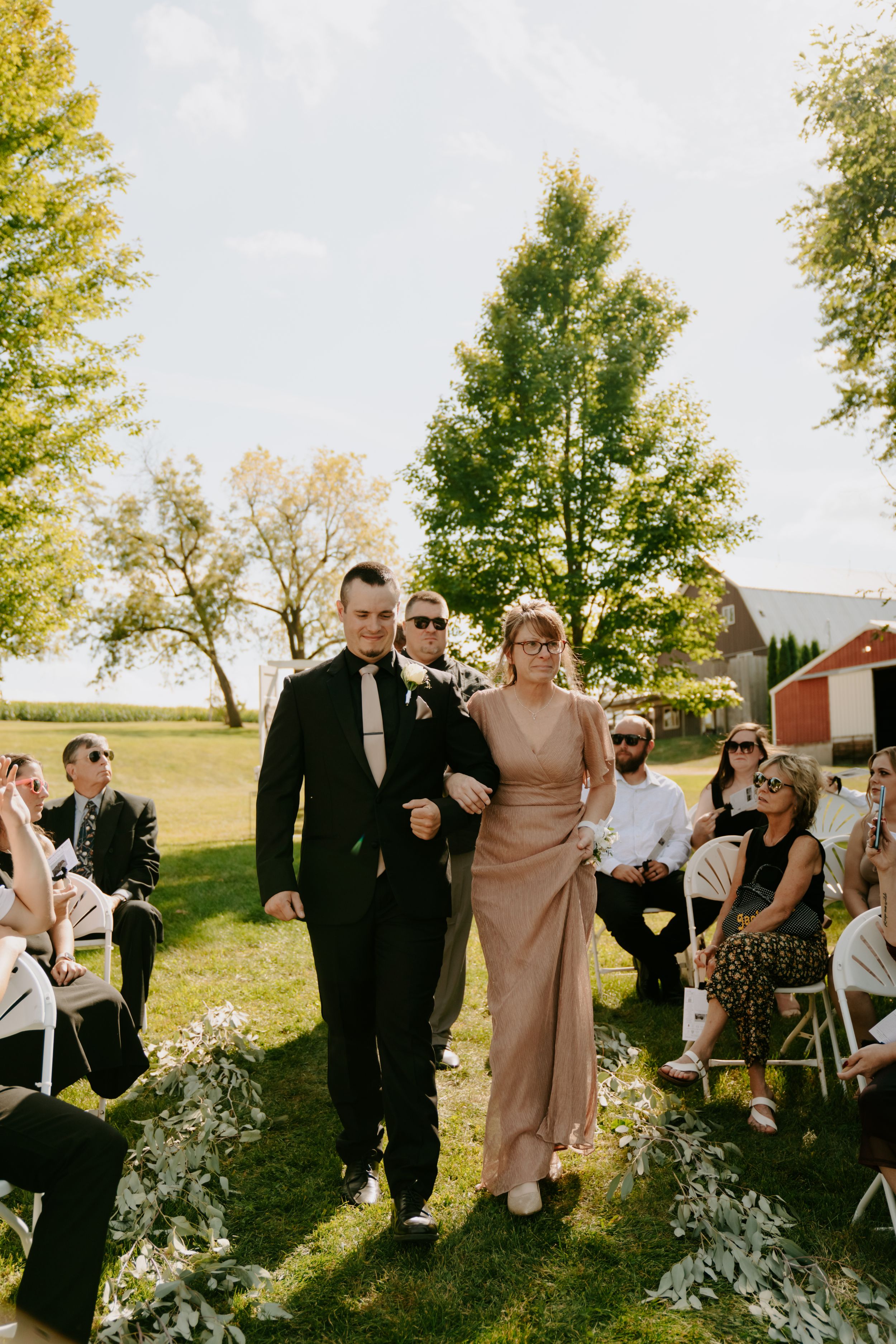 Wedding guests and party members walking through sunny outdoor venue.