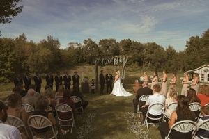 Panoramic view of an outdoor wedding ceremony with white chairs and natural landscape.