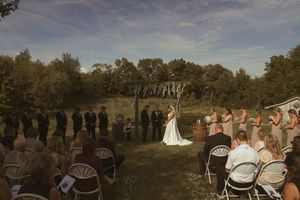 Wedding guests seated in white chairs during an outdoor ceremony with scenic backdrop.