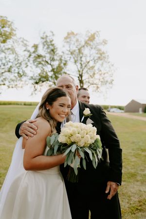 Tender moments captured during outdoor wedding ceremony with white floral bouquet.
