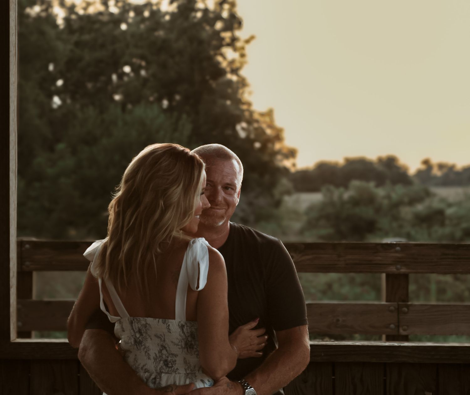 A romantic sunset moment shared on a wooden deck overlooking a scenic natural landscape.