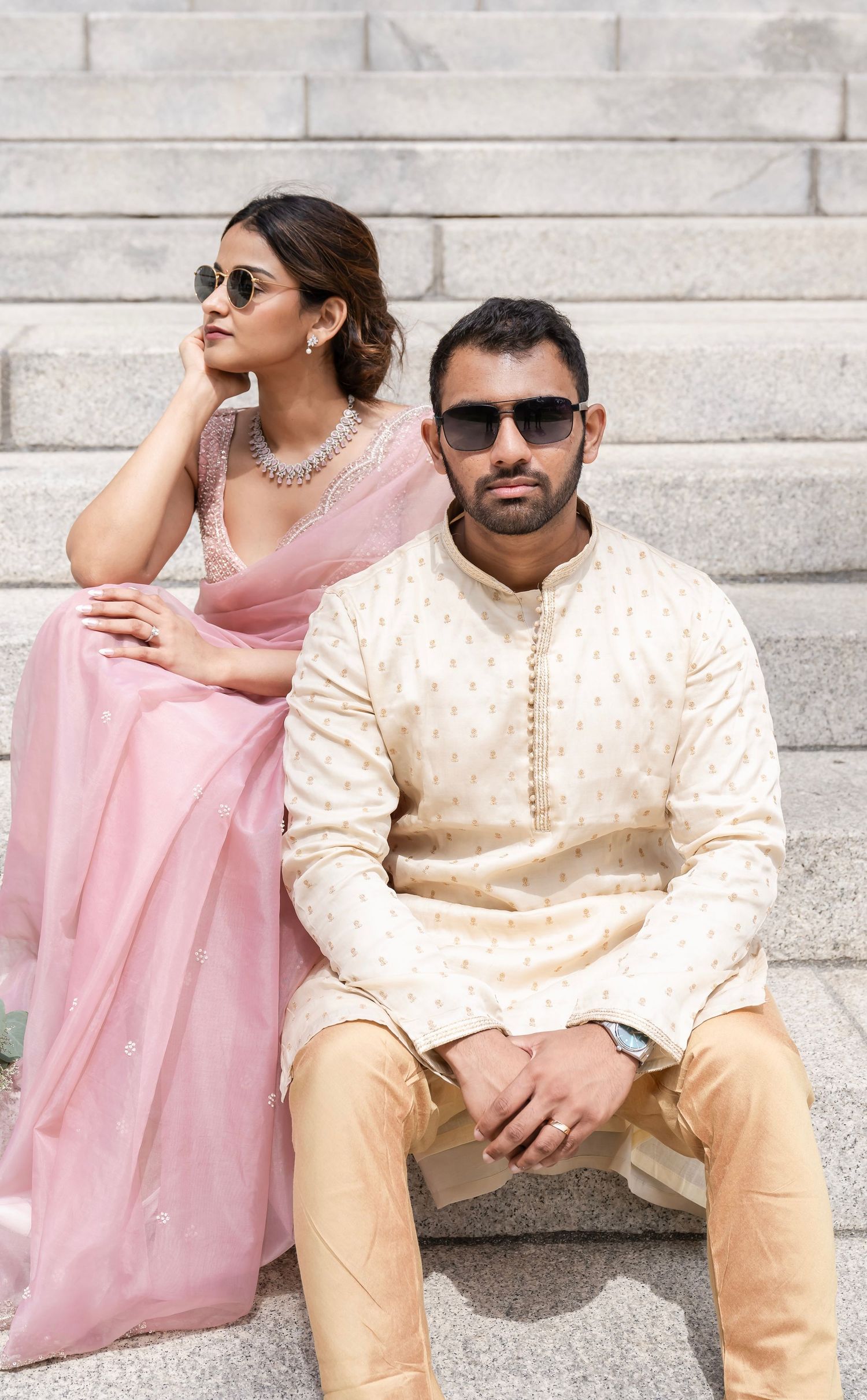 A couple embraces in formal attire during an outdoor portrait session with soft bokeh lighting in the background.