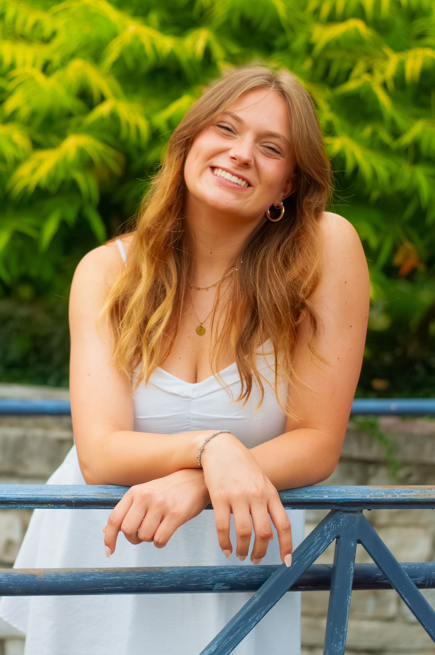 A woman wearing a graduation robe sitting on stone steps