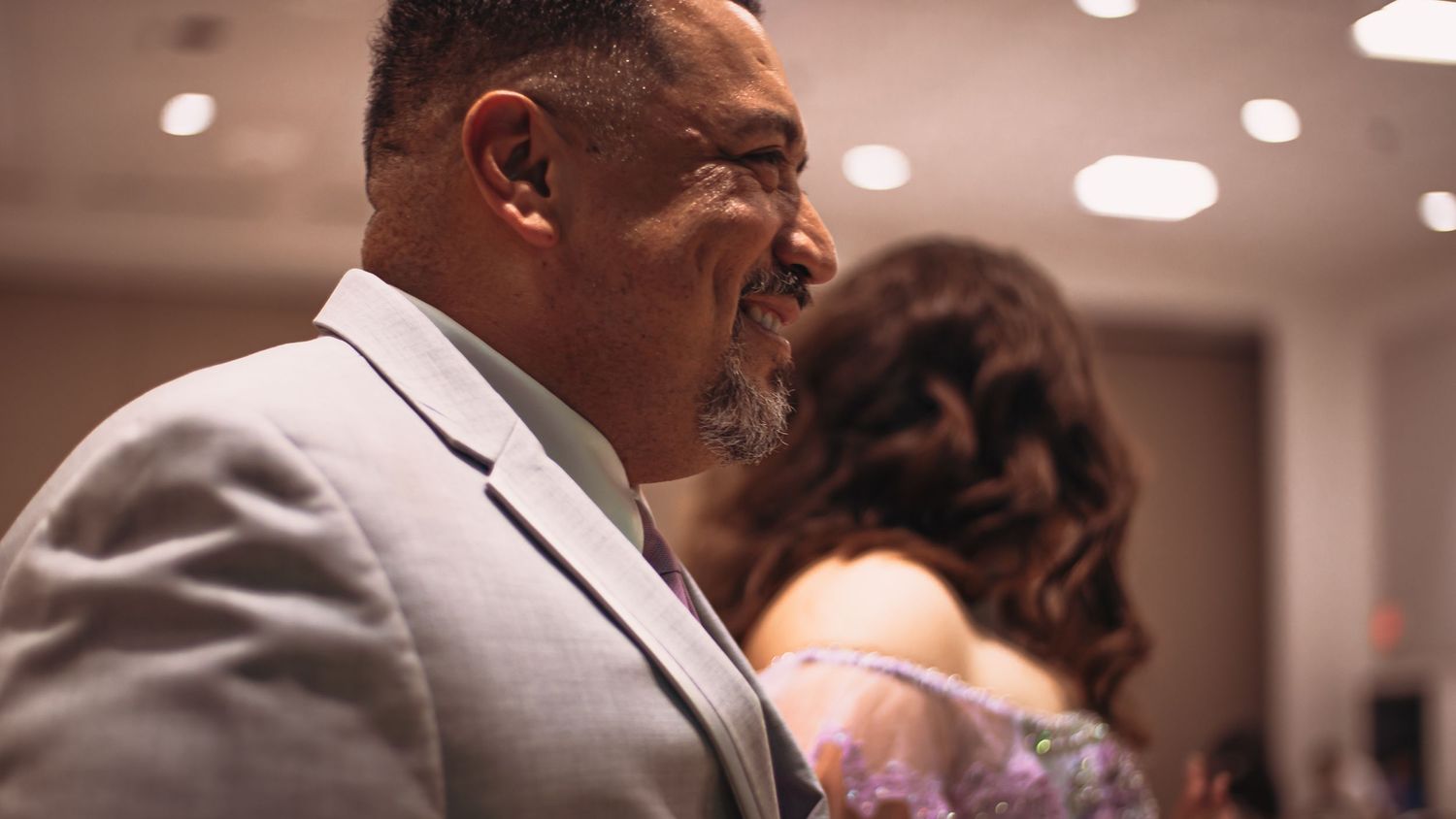 A candid moment captured at an indoor event shows someone in a light gray suit.