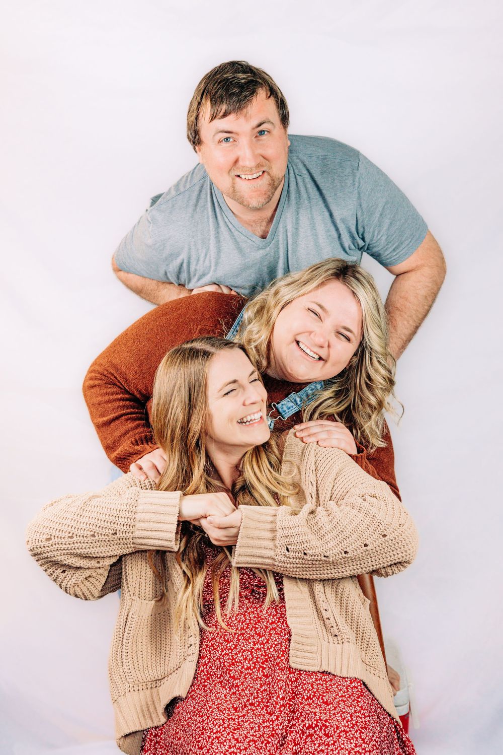 Playful family portrait with casual poses against white background.