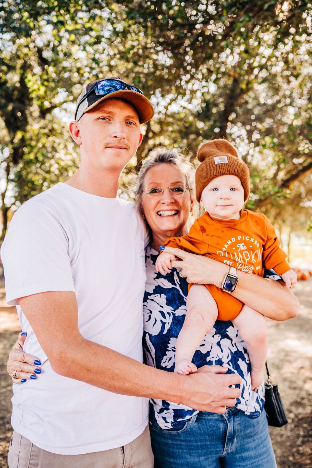 Outdoor family portrait in casual attire against sunlit natural background.