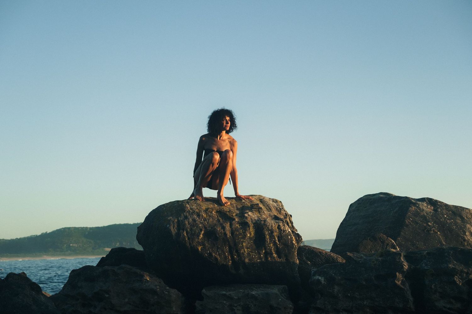 Lifestyle Photography - Candid lifestyle session capturing woman enjoying morning sun on rock face at Palm Beach, Sydney