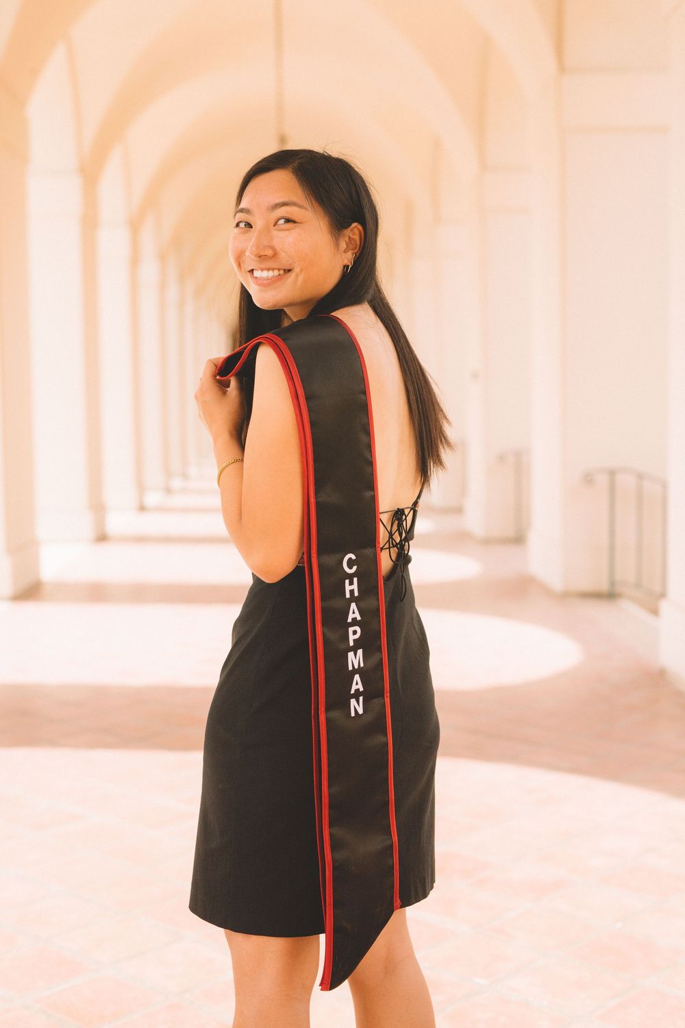 Person in black dress with Chaman text poses in arched hallway.