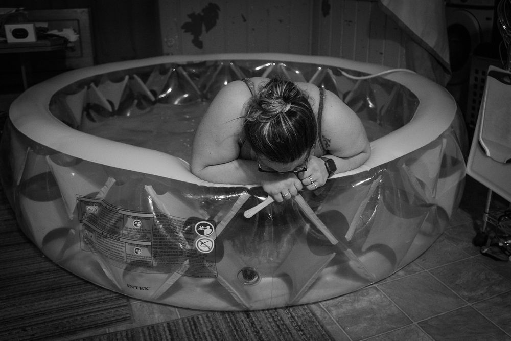Person relaxing in an inflatable pool indoors with decorative patterns.