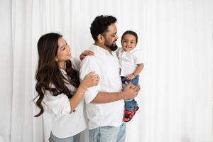 A family wearing white tops poses together against a white backdrop, creating a bright and cheerful portrait.