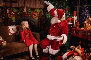 Santa Claus sitting on wooden bench with decorated Christmas tree and stockings in cozy holiday setting.