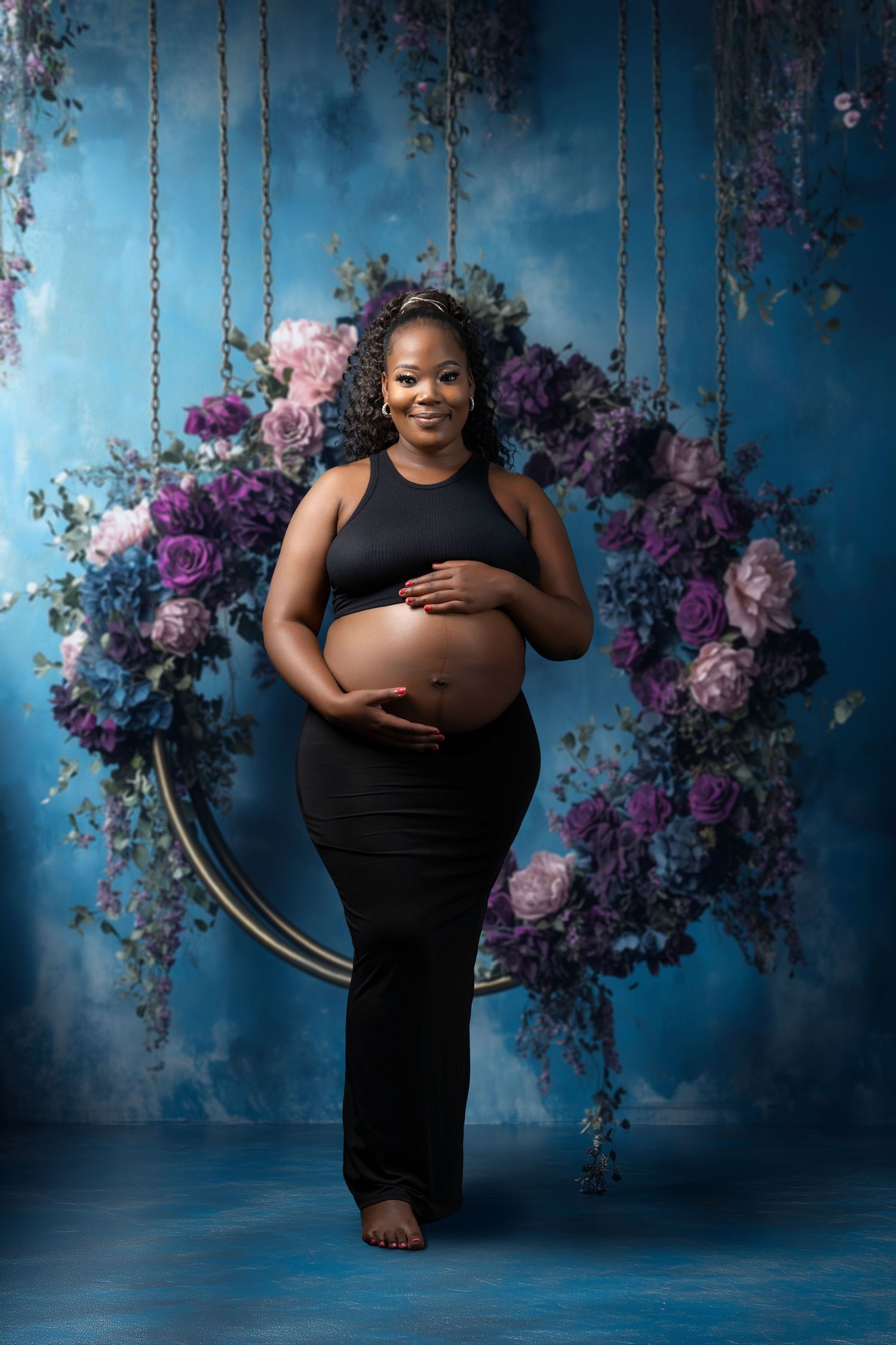 Maternity photoshoot with floral backdrop and dramatic blue lighting.