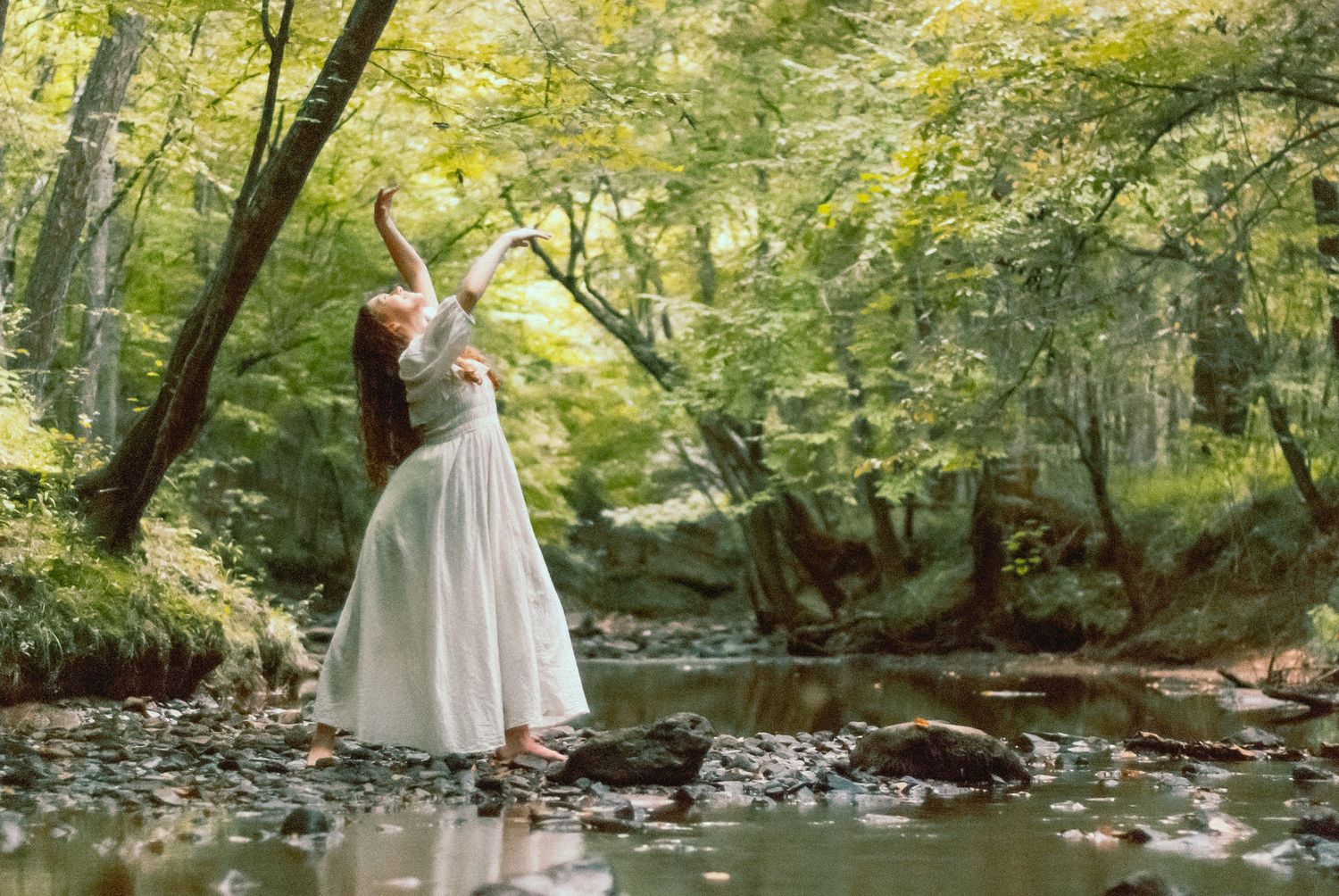 Woman dancing in the woods by a creek in Charlotte, North Carolina at full creative storytelling photo session