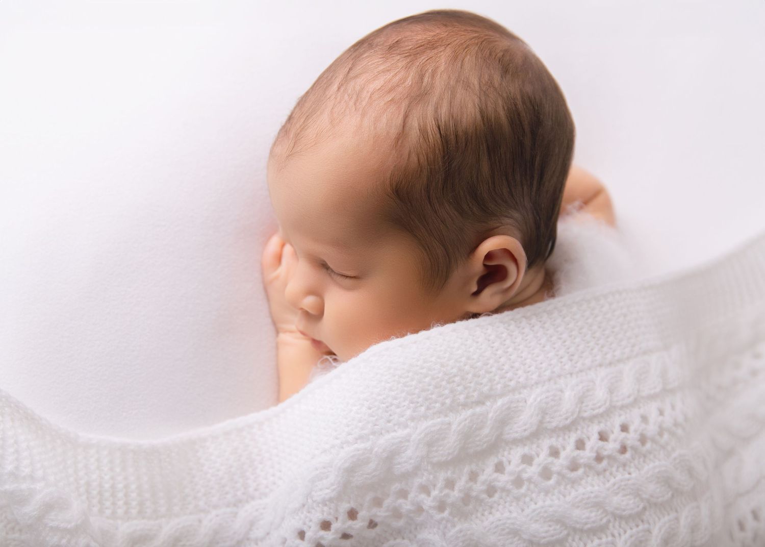 Newborn asleep with blanket.