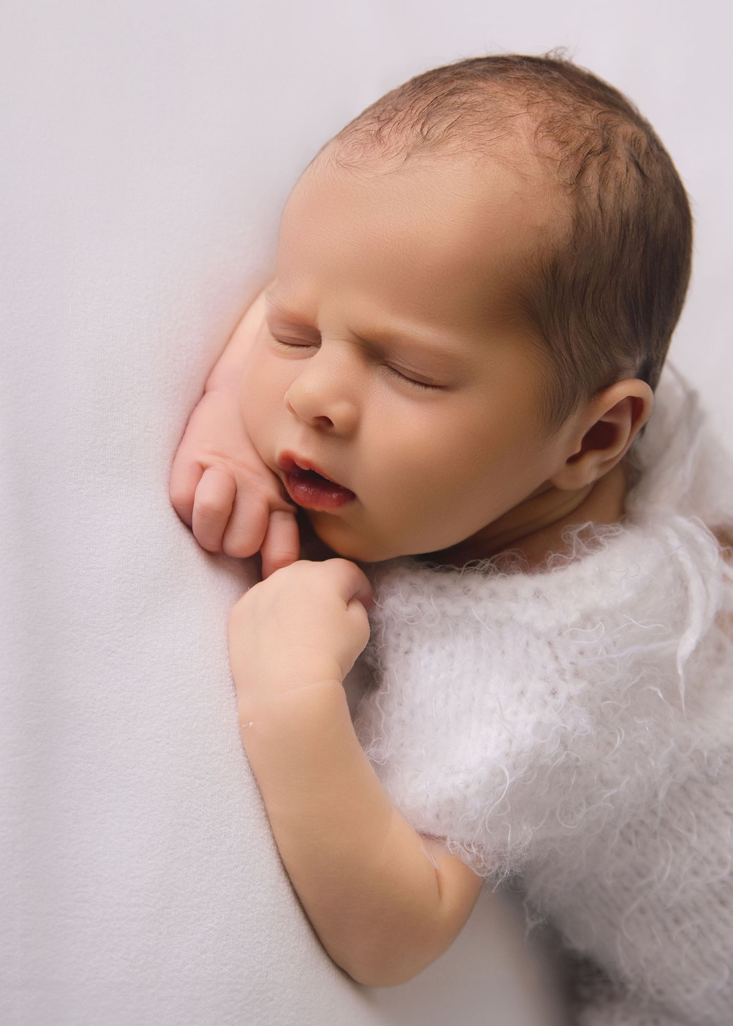 Newborn fast asleep on arms.