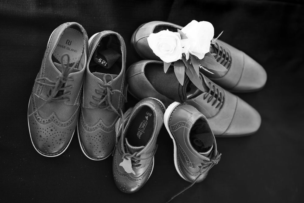 Black and white photo of formal dress shoes arranged for a wedding.