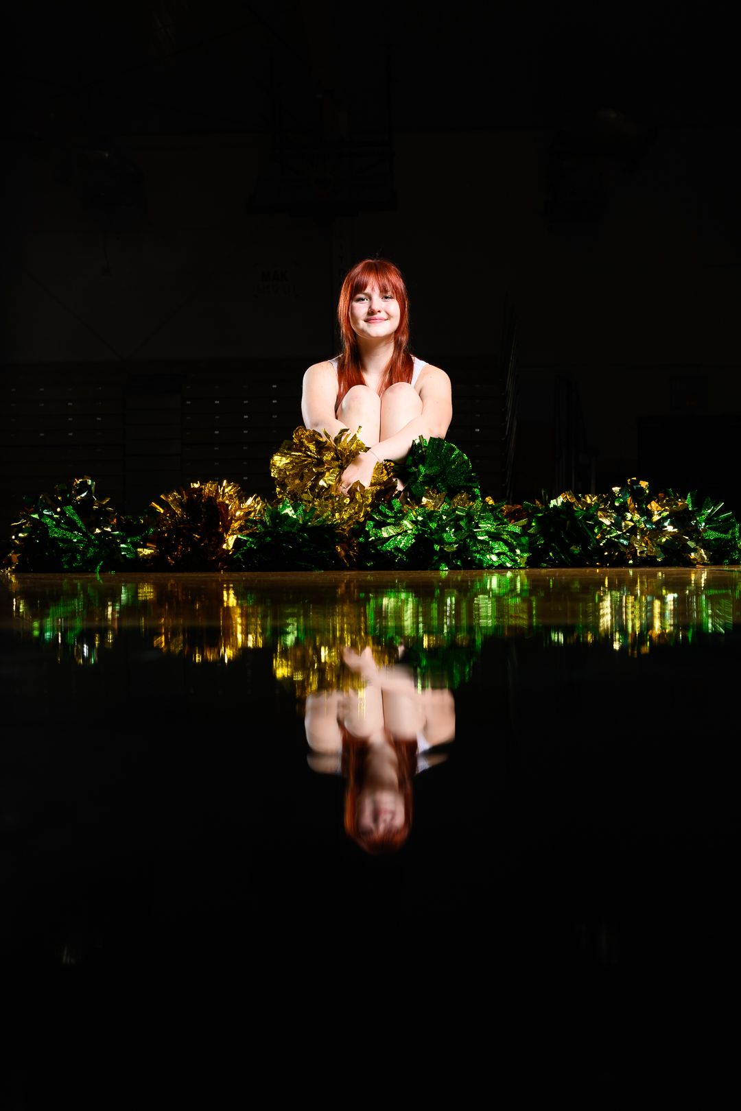 Artistic nighttime portrait with woman surrounded by glowing greenery reflecting on water surface.