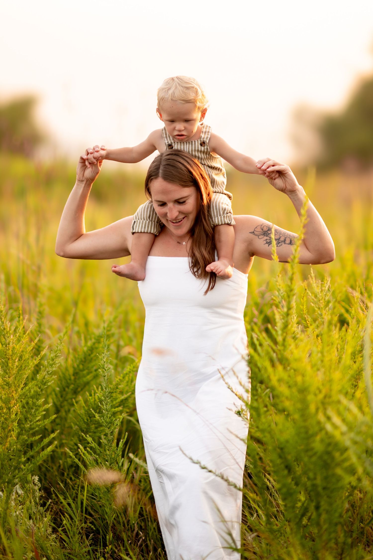 A carefree parent and child playing together in a sunny field filled with tall green plants on a summer day.