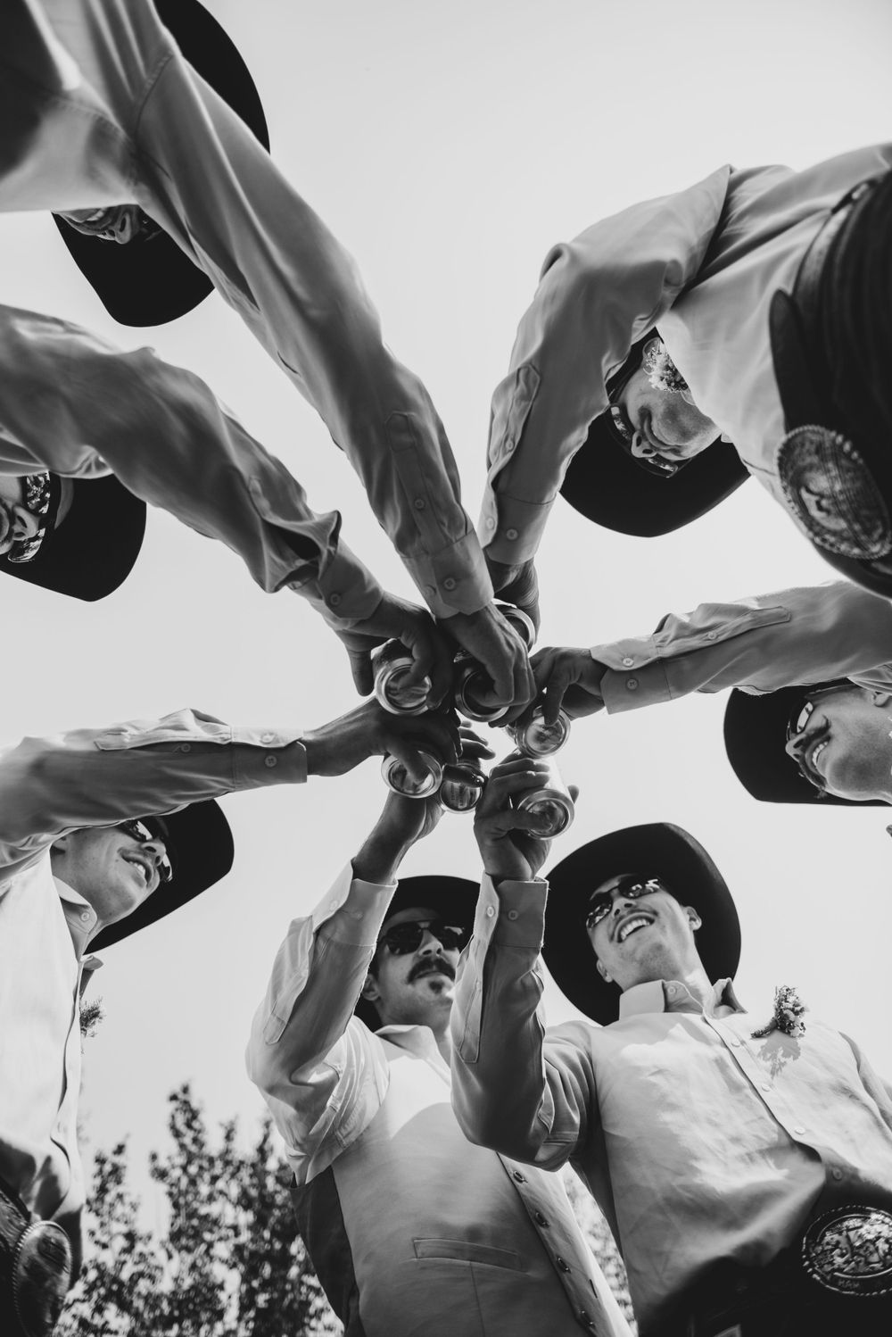 A black and white photo showing hands joining together in a circle from below.
