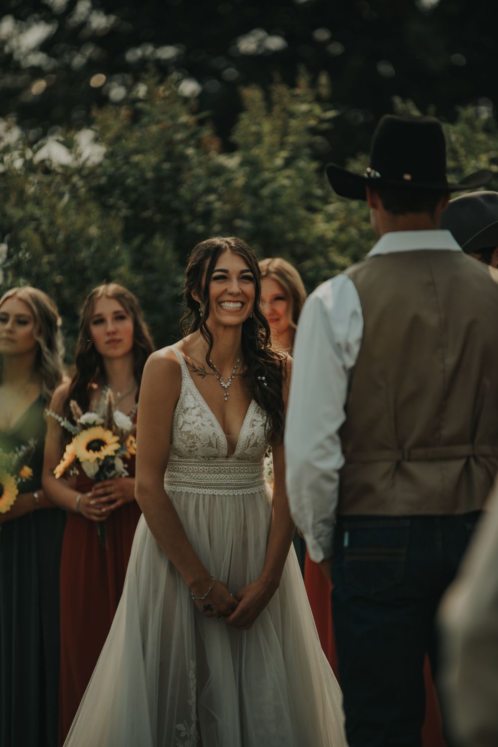 Wedding ceremony scene with bridesmaids in burgundy dresses and sunflowers.