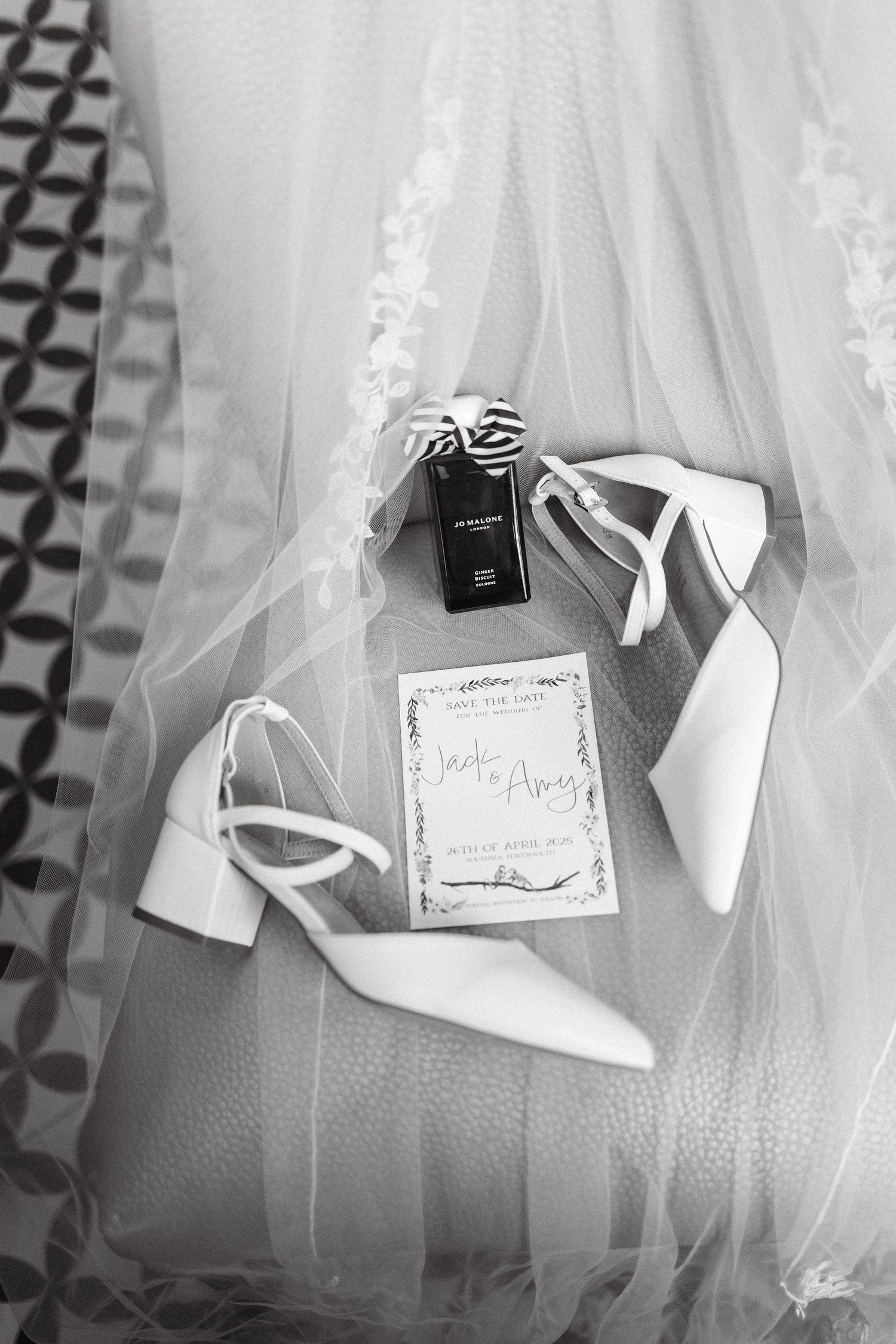Wedding accessories including white shoes, cards and ribbons arranged on a textured surface.