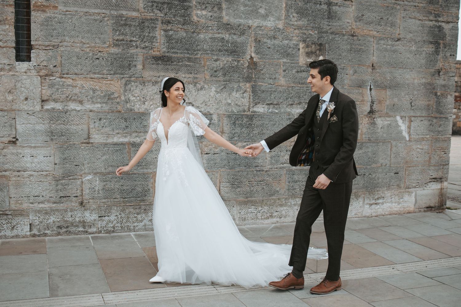 Wedding couple poses against stone wall backdrop in romantic photo sequence.