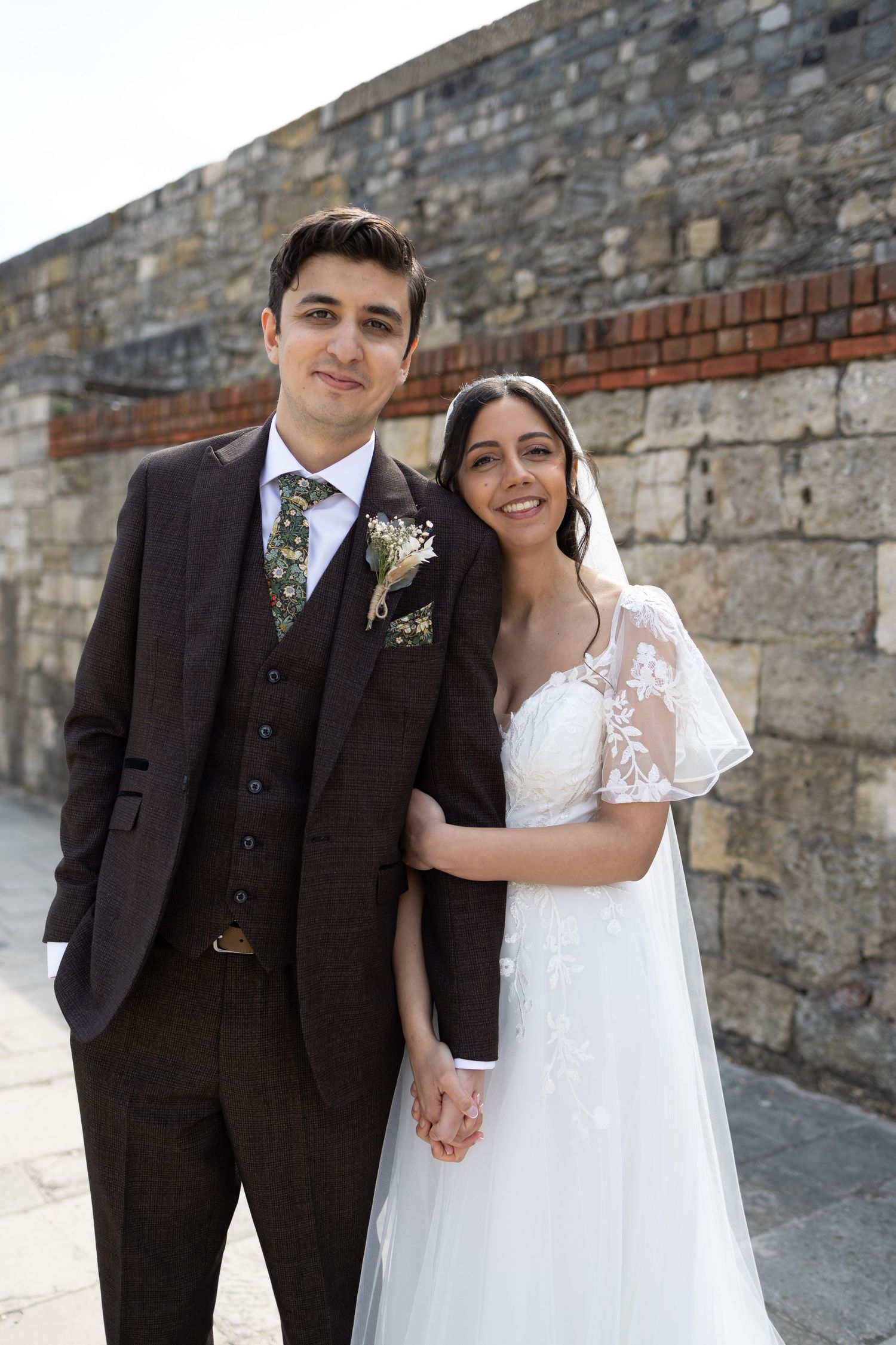 Romantic wedding portrait sequence against stone wall background.