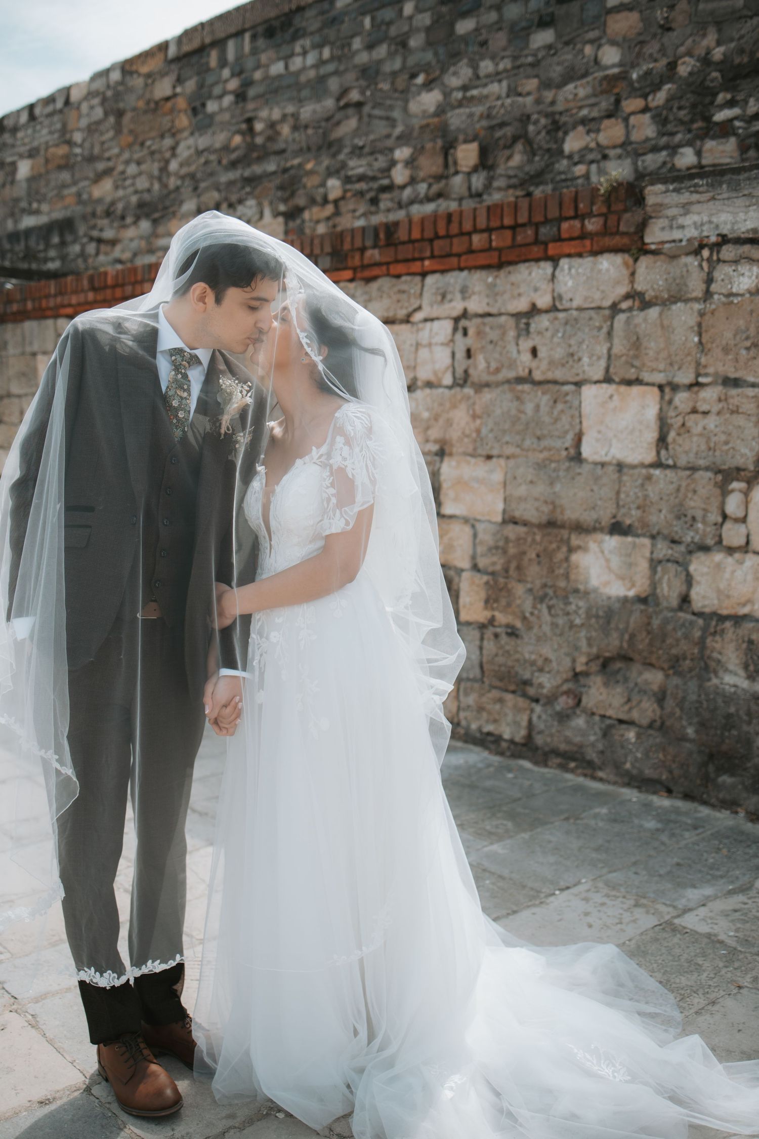 Intimate wedding couple portraits against historic stone wall backdrop.