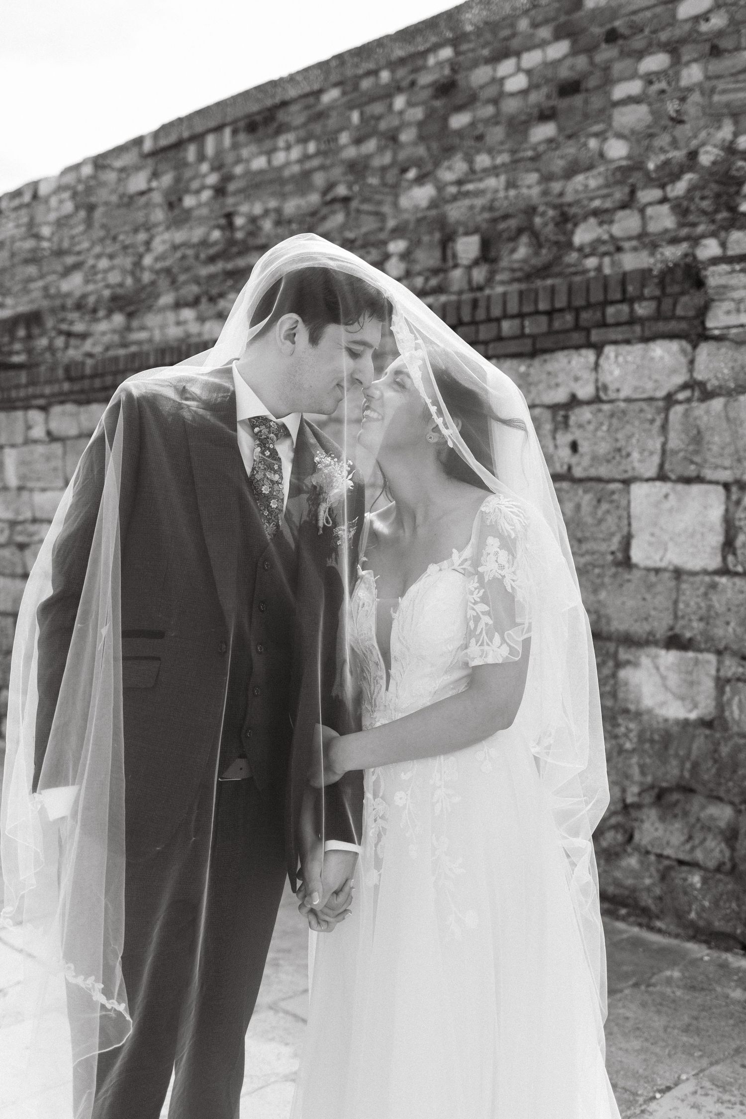 Artistic black and white sequence of couple's romantic moments against stone wall.