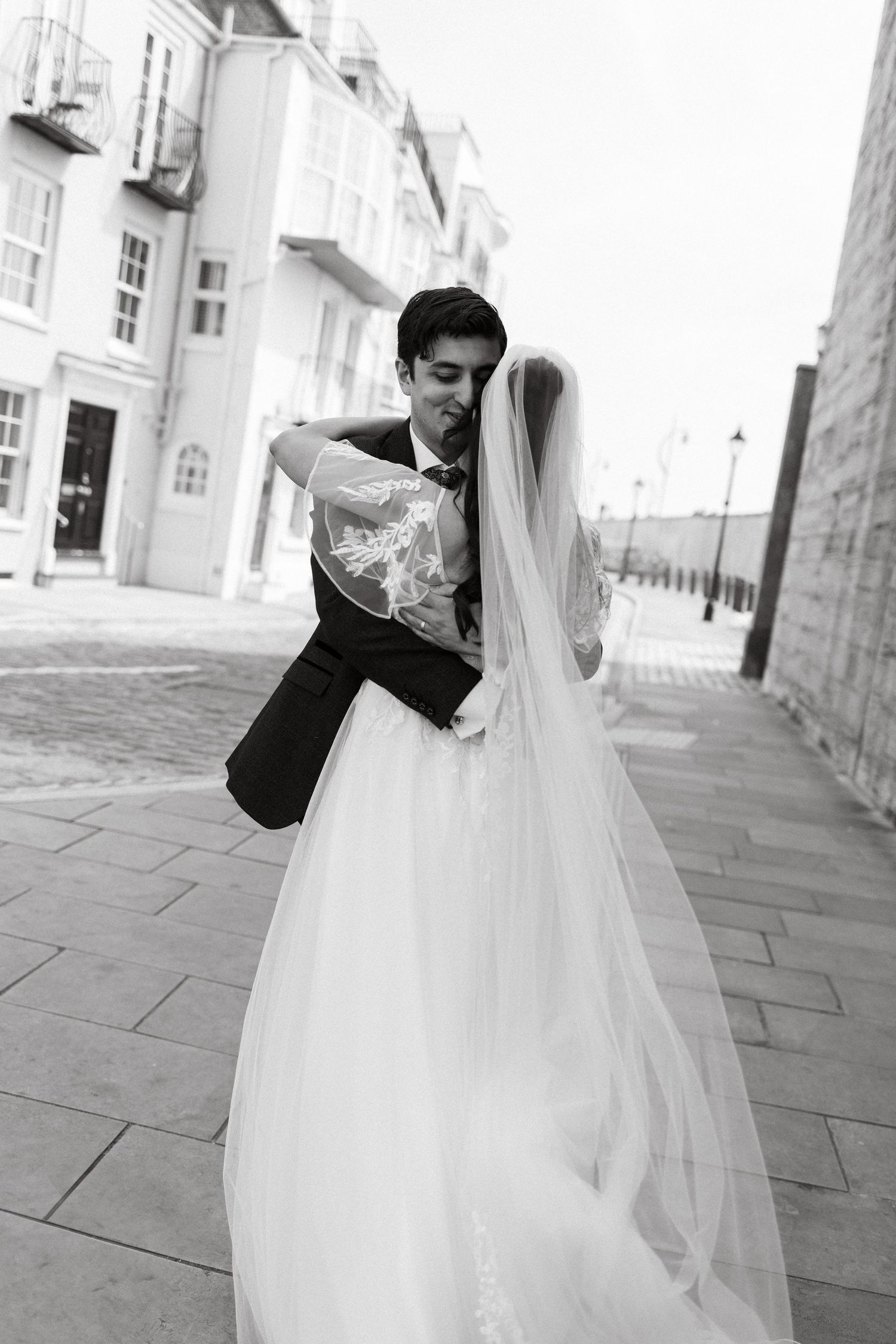 A dramatic black and white wedding photo showing a couple dancing on a city street.