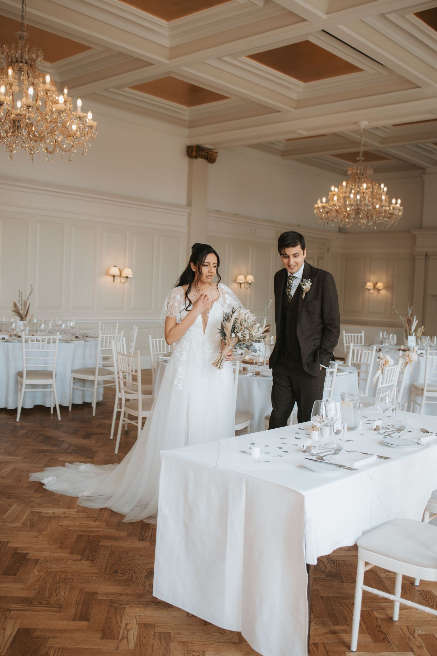 Elegant wedding reception venue with crystal chandeliers and white table settings.