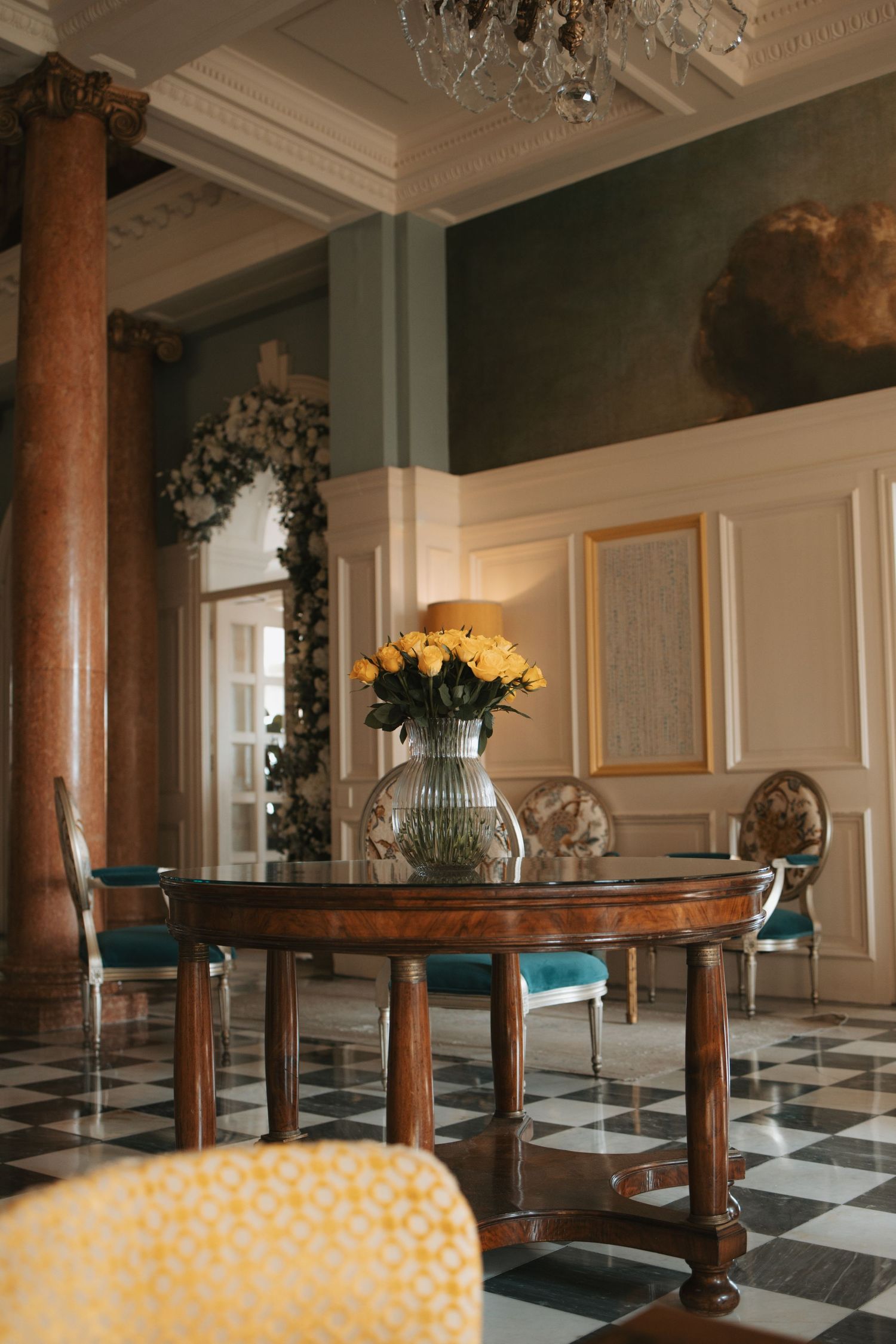 Luxurious ballroom interior with marble columns and checkered floor pattern.