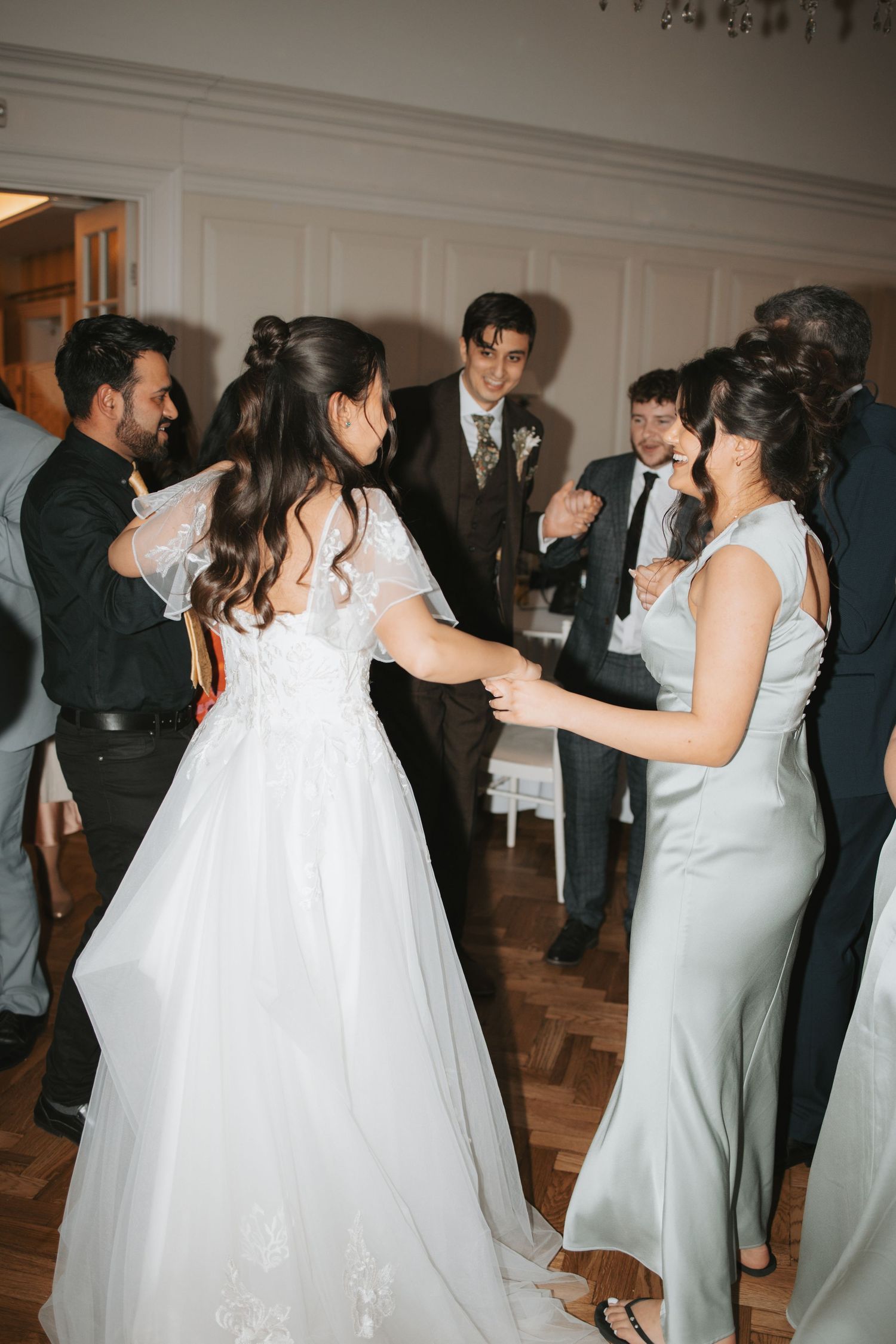 Wedding party members in formal attire dancing in an elegant ballroom setting.