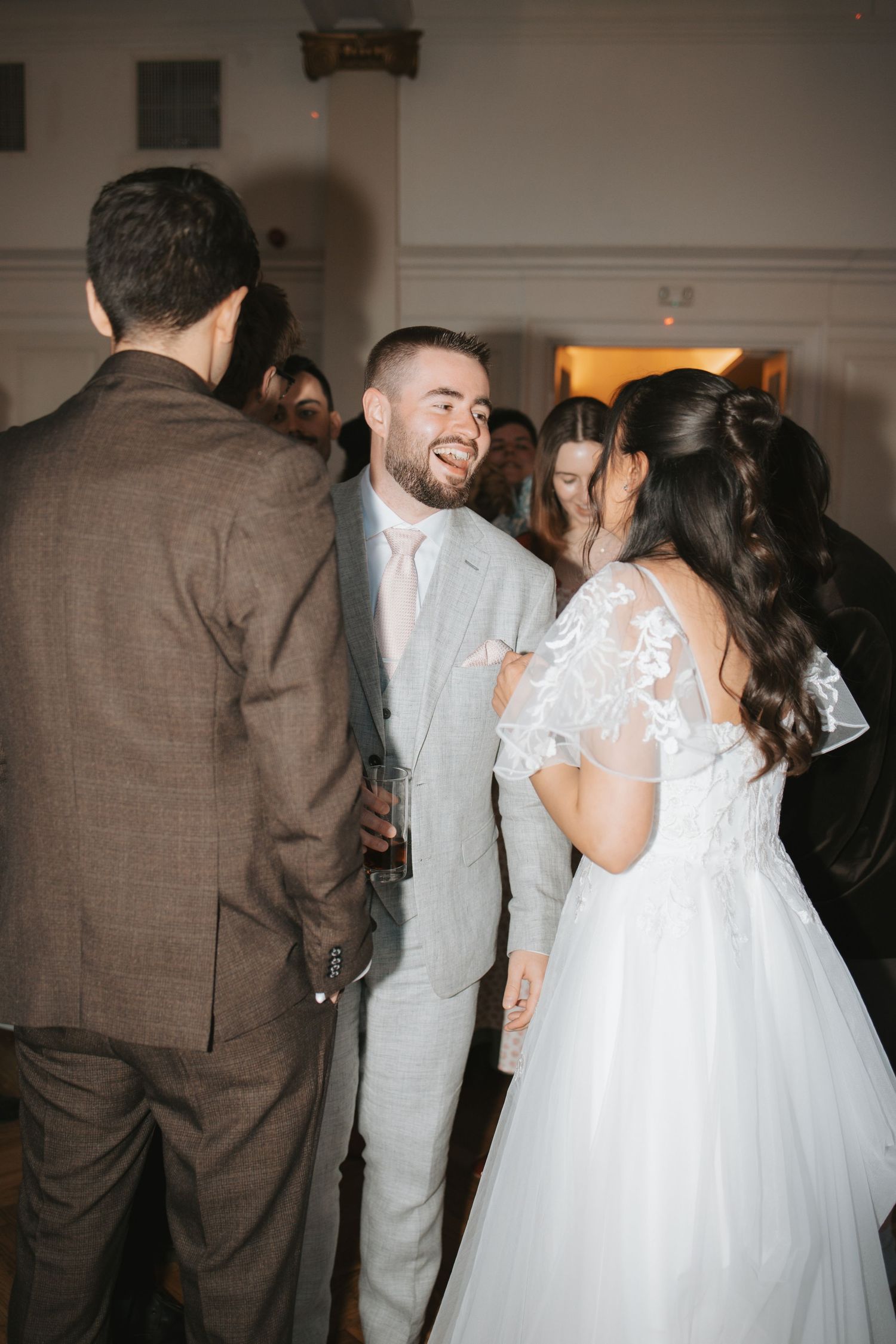 Wedding celebration with guests dancing and enjoying festivities in an indoor reception venue.
