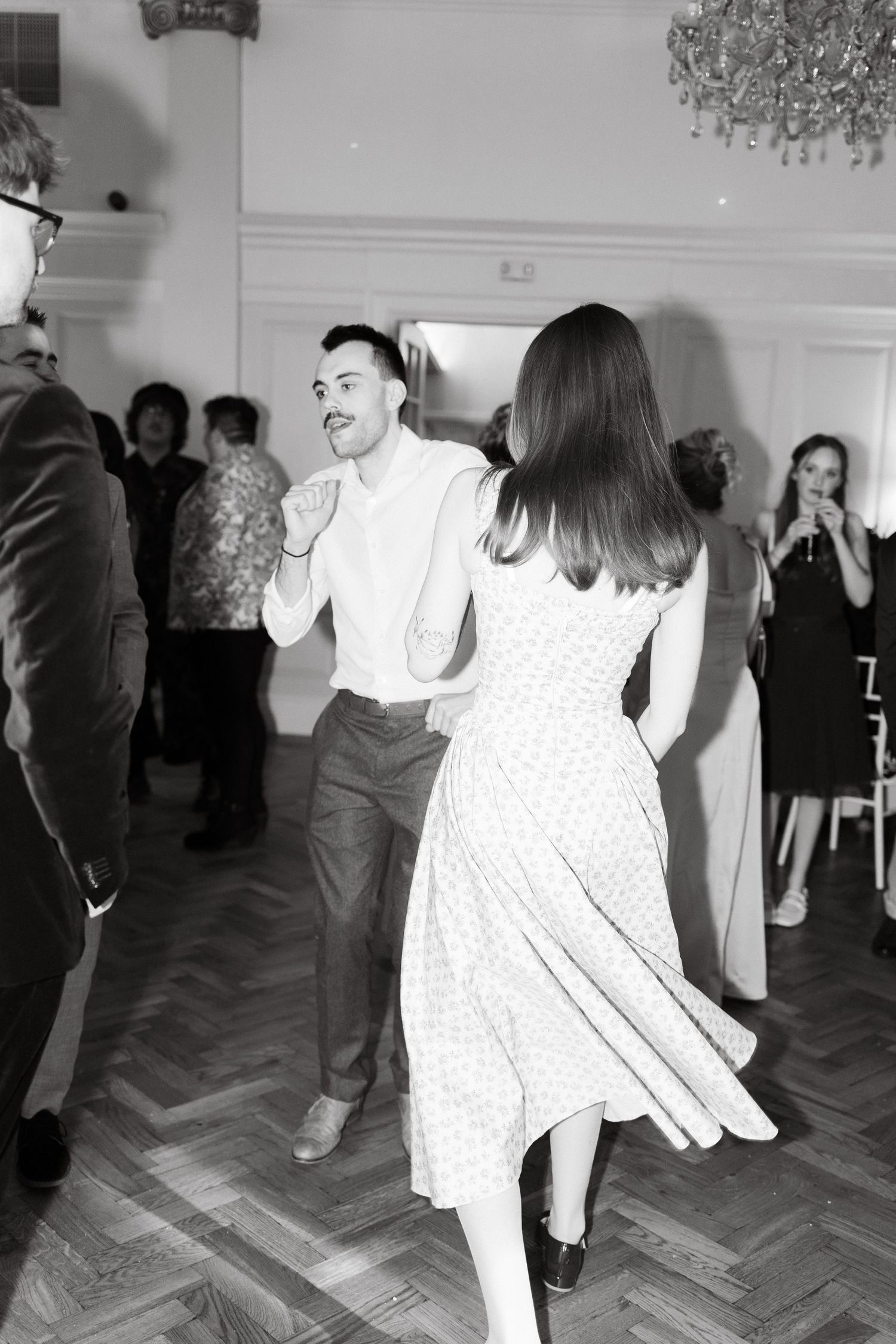 Black and white photos of people dancing at an indoor event with parquet flooring.