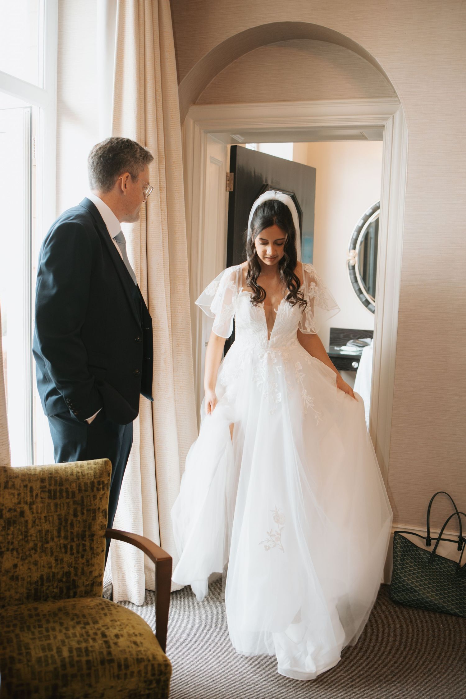A wedding dress swishes through an elegant hallway with arched doorways and vintage furniture.