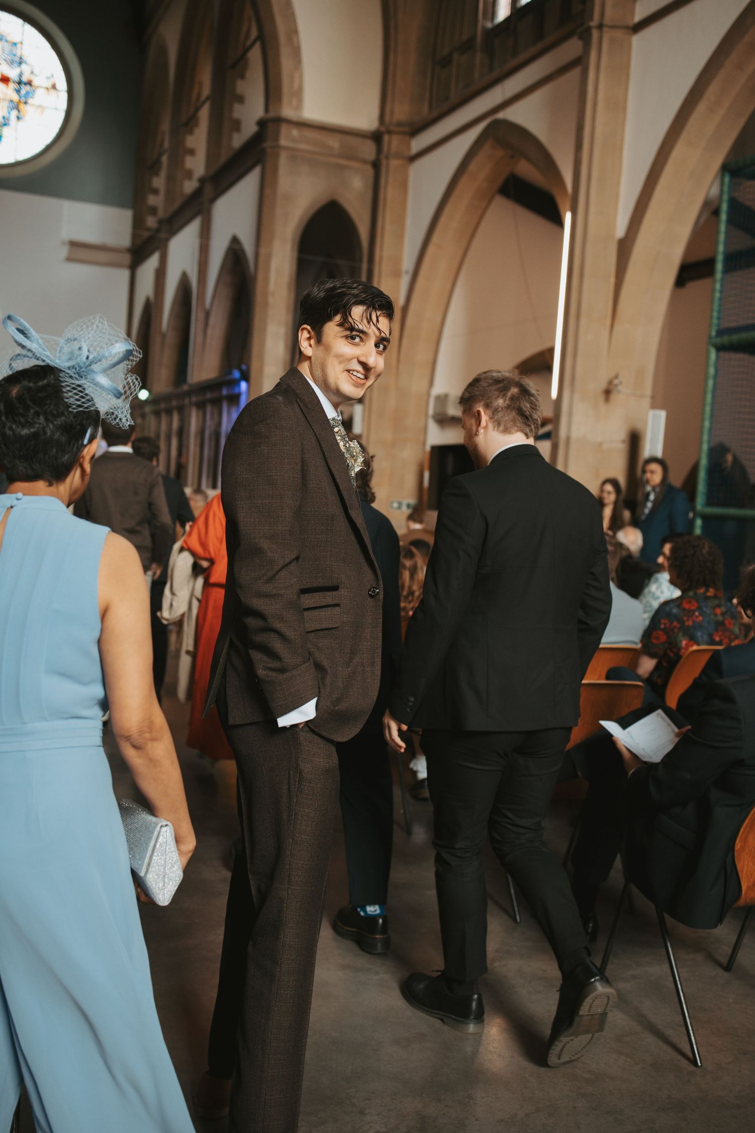 Guests mingle inside a grand church with arched architecture during a wedding ceremony.